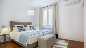 Une chambre à coucher moderne avec un grand lit, des lampes de chevet, une fenêtre avec des rideaux et un plancher en bois.