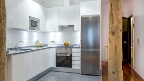 Une cuisine moderne avec des armoires blanches, des appareils en acier inoxydable et un mur d’accent en bois.