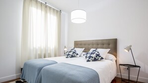 A bedroom with a large bed, two bedside lamps, and a window with curtains. - Superior 2 Bedroom Apartment - Chueca (Chueca)