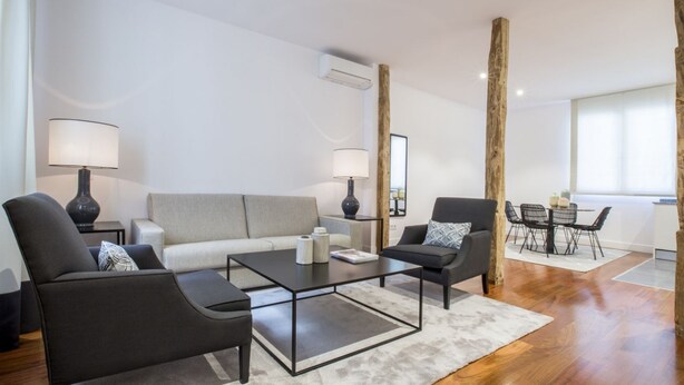 A modern living room with a sofa, two armchairs, a coffee table, and a dining area with a table and chairs. - Superior 2 Bedroom Apartment - Chueca (Chueca)