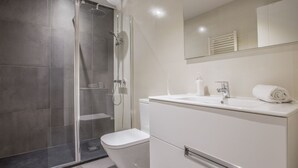 A modern bathroom with a glass-enclosed shower, a white toilet, and a vanity with a mirror. - Superior 2 Bedroom Apartment - Chueca (Chueca)