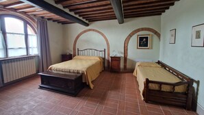 Una habitación con dos camas, un aparador, un radiador y una ventana con cortinas.