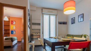 Ein kompakter Wohnraum mit Essbereich, Küchenzeile und einer kleinen Sitzecke mit Sofa und Sesseln.