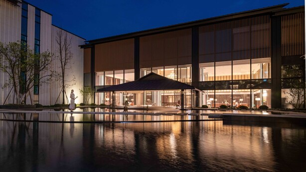A modern building with a reflective pool, large windows, and a covered outdoor seating area. - Nanhu Hotel (Jiaxing)