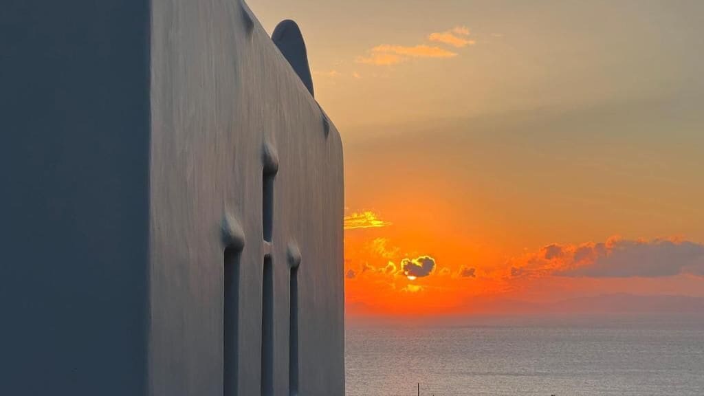 A sunset over the ocean with a building in the foreground.