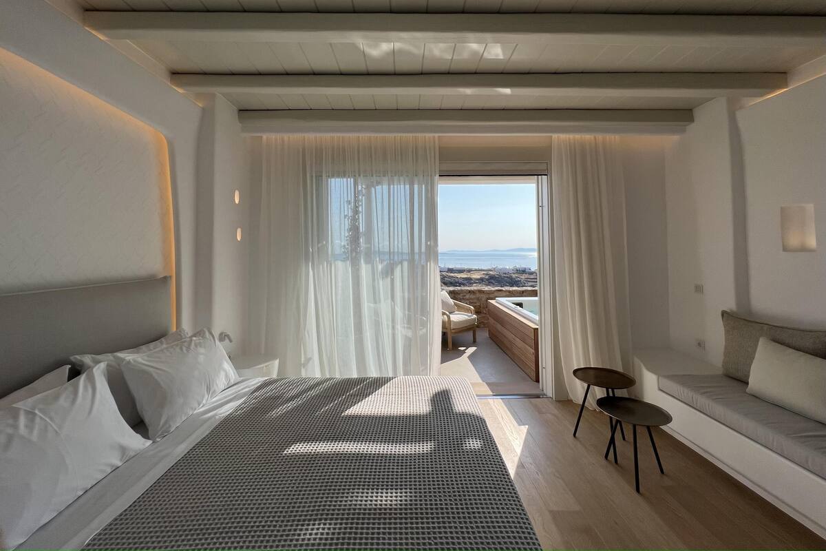 Une chambre moderne avec un grand lit, un petit canapé et une vue sur la mer.