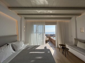 Un dormitorio moderno con una cama grande, un sofá pequeño y vistas al mar.