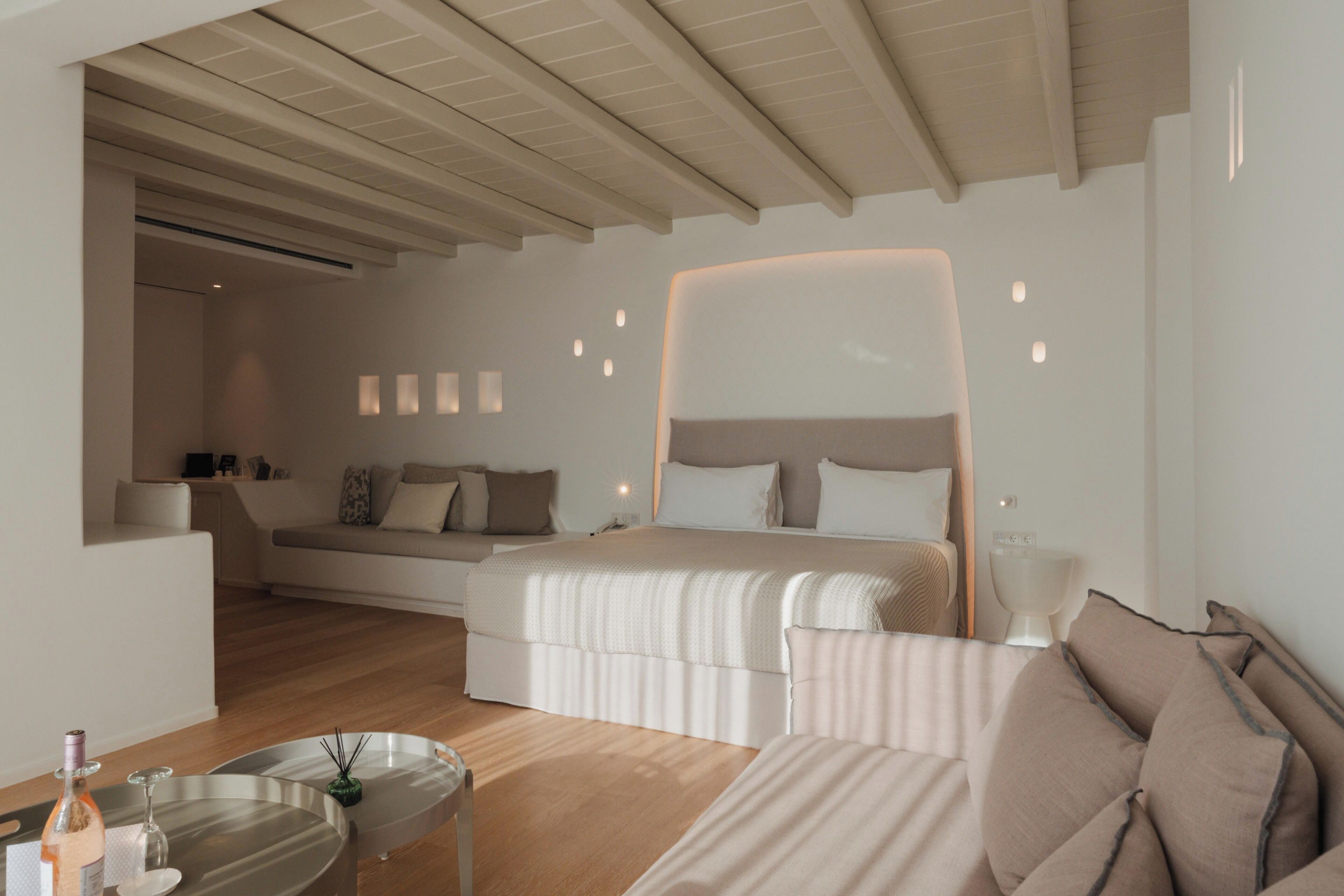 A modern bedroom with a large bed, bedside tables, and a seating area with a sofa and a small table.