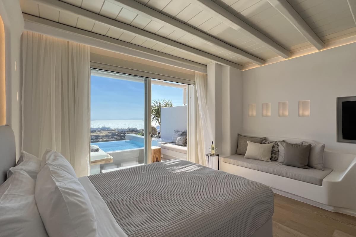 Une chambre moderne avec un grand lit, une télévision et une vue sur la mer.