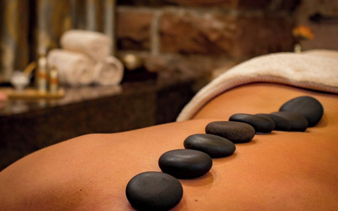 A massage table with black stones placed on a person's back.