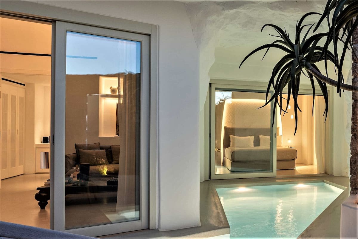 Un intérieur moderne avec une porte vitrée donnant sur une chambre, un petit espace piscine et une plante en pot.