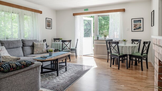 A modern living room with a sofa, coffee table, and dining area with chairs and a table. - Vandrarhemmet Stranden i Mora (Mora)