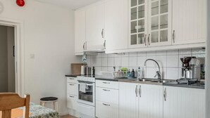 A compact kitchen with white cabinets, a stove, and a sink. - Vandrarhemmet Stranden i Mora (Mora)
