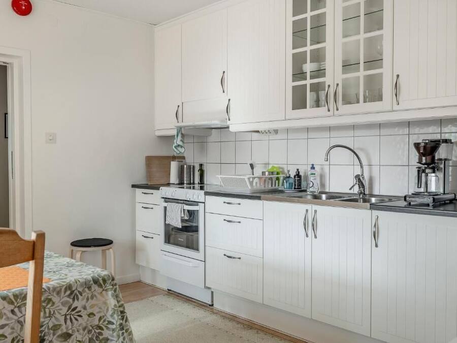 Una cocina compacta con gabinetes blancos, una estufa y un lavamanos.