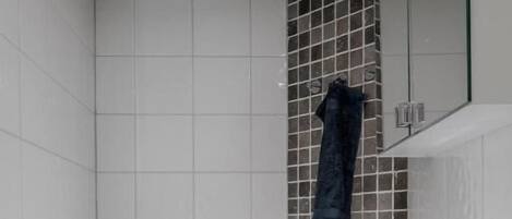 A bathroom with a white toilet, a sink with a mirror, and a towel hanging on the wall.