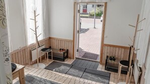 A room with a wooden floor, a bench, a small table, a door leading outside, and a window with sheer curtains. - Vandrarhemmet Stranden i Mora (Mora)