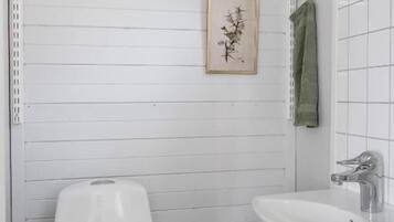 A bathroom with a toilet, a sink, a towel rack, and a framed picture on the wall.