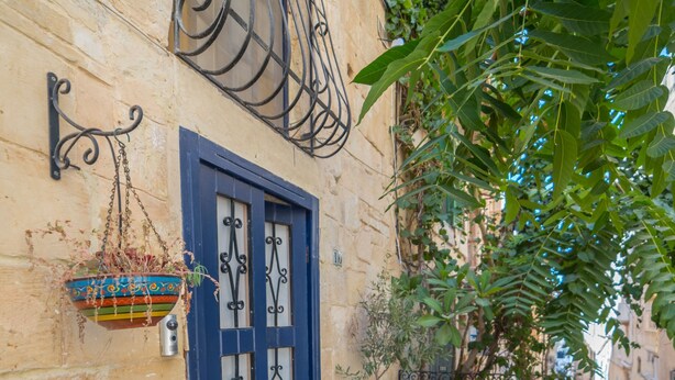 A small outdoor seating area with a blue door, potted plants, and a wooden bench. - PA - Pandora Loft  (Valletta)
