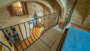 A stone-walled room with a wooden staircase and a blue carpet. - PA - Pandora Loft  (Valletta)
