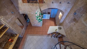 A stone-walled interior with a kitchen area, a staircase, and a hanging light fixture. - PA - Pandora Loft  (Valletta)