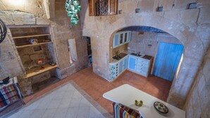 A compact kitchen with stone walls, a small dining area, and a built-in sink. - PA - Pandora Loft  (Valletta)
