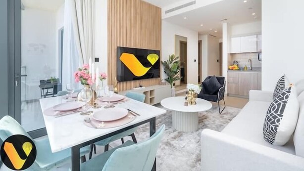 Moderni olohuone, jossa on ruokailutila, sohva, televisio ja taustalla keittiö.