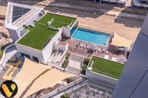 Et moderne hotel med tagpool, grønne områder og udendørs siddepladser.