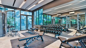 Un gimnasio moderno con diversos equipos de ejercicio, ventanas amplias y vistas a la ciudad.