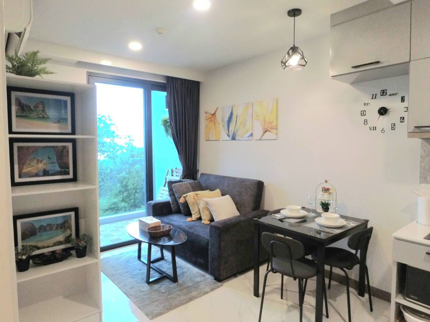 A modern living room with a sofa, a dining table with chairs, and a large window.