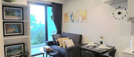 A modern living room with a sofa, a dining table with chairs, and a large window.