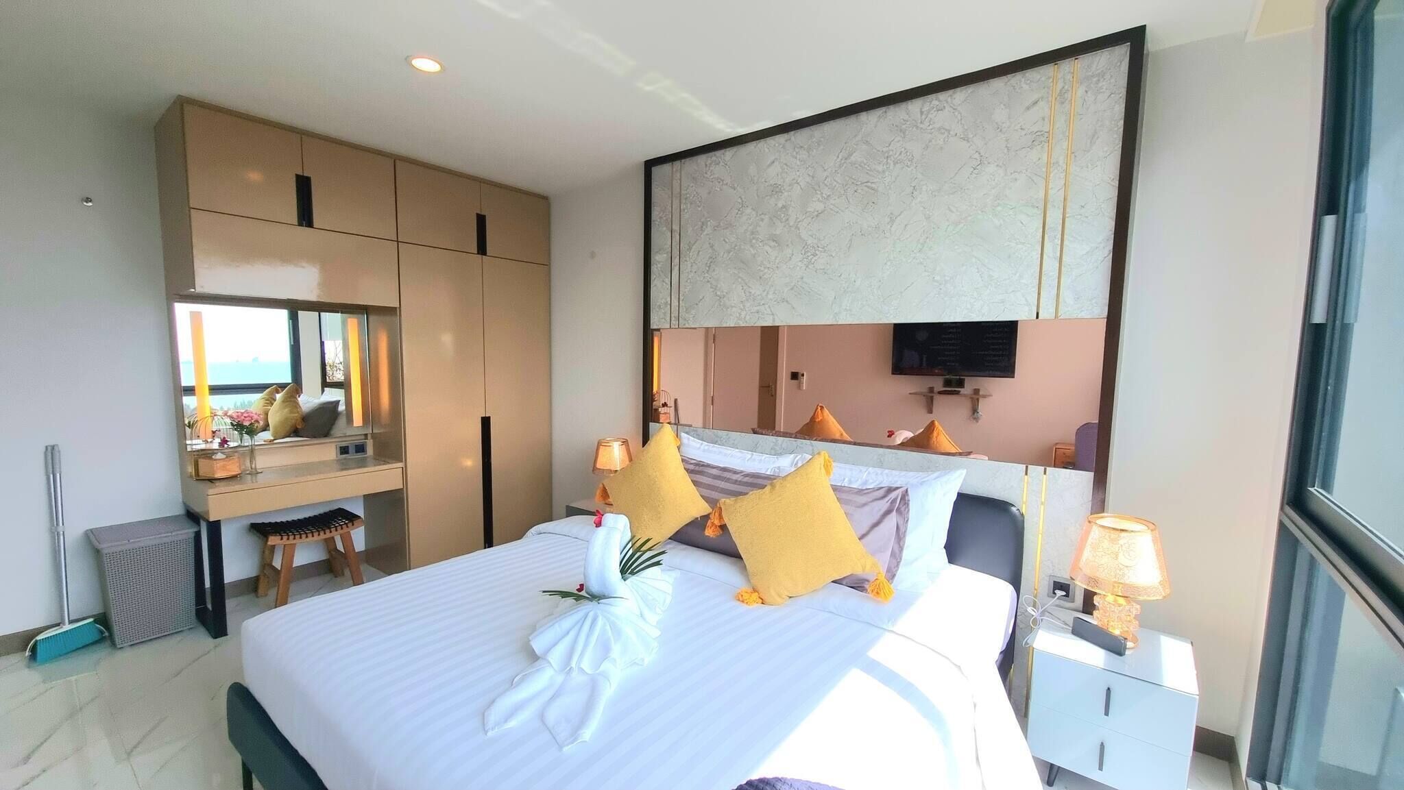 Habitación de hotel con una cama grande, un escritorio, un espejo y un televisor en la pared.