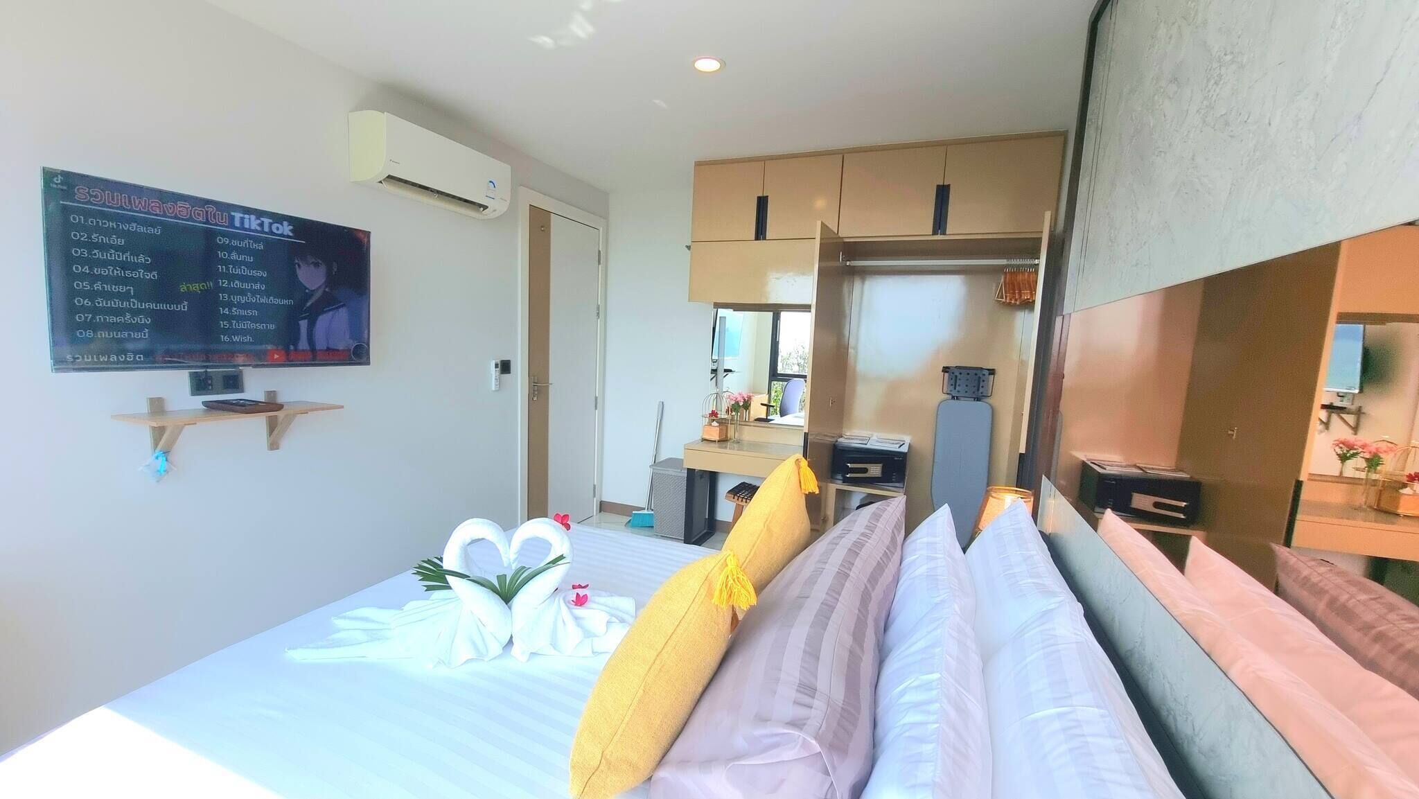 Una habitación de hotel con cama, escritorio, tabla de planchar y aire acondicionado instalado en la pared.