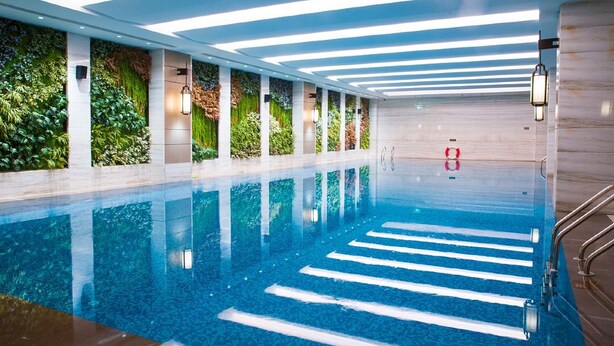 Une piscine intérieure avec des couloirs bien délimités, entourée de murs agrémentés de jardins verticaux et d’un éclairage moderne.