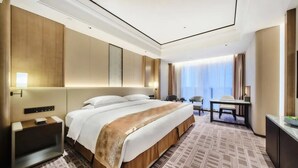 Une chambre d’hôtel avec un grand lit, un bureau et une télévision.