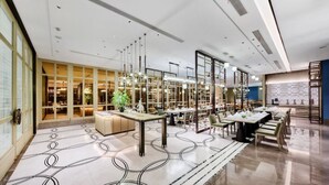 Un hall d’hôtel moderne doté d’un vaste espace salon, d’un comptoir d’accueil et d’une grande fenêtre donnant sur l’intérieur.