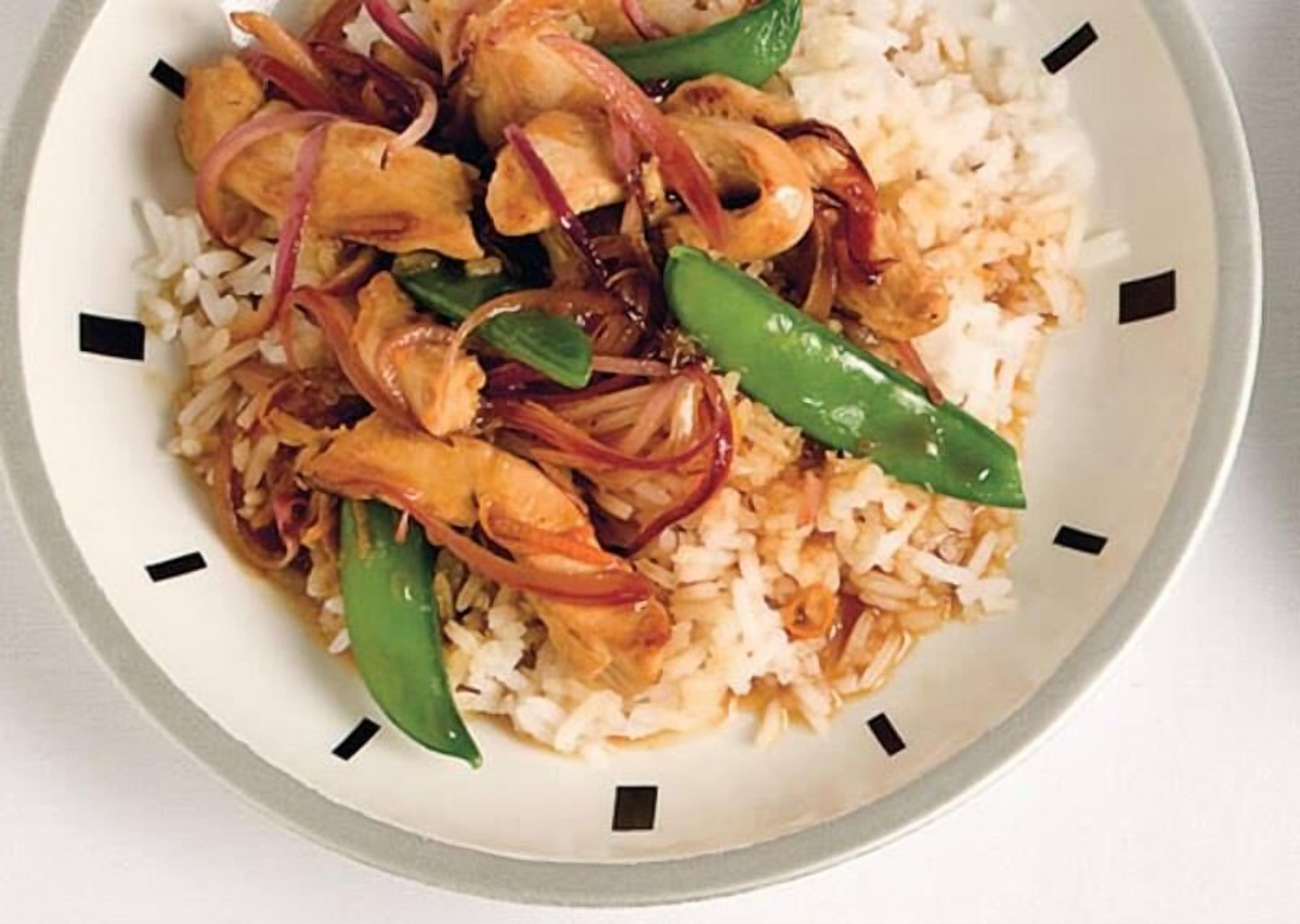 A plate of stir-fried chicken with vegetables and rice.