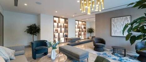 Un salon moderne comprenant un canapé, des fauteuils, une table basse et une plante décorative.