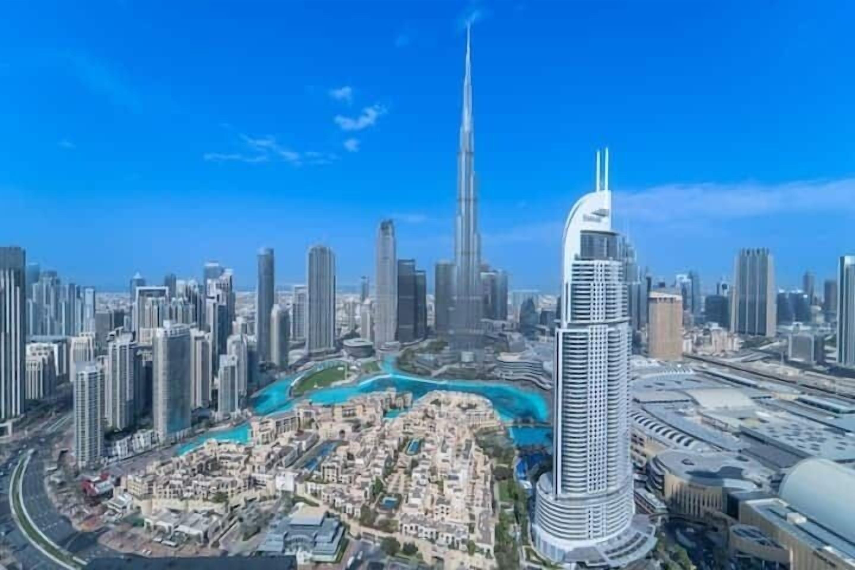 A high-rise building with a unique curved design, surrounded by a dense urban area with other skyscrapers.