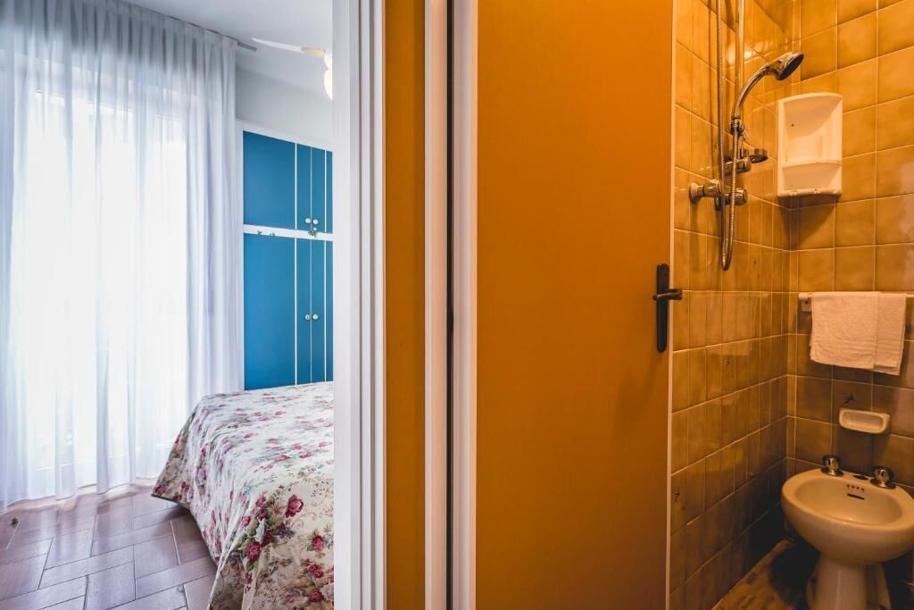 A bathroom with a shower, a sink, and a blue wardrobe.