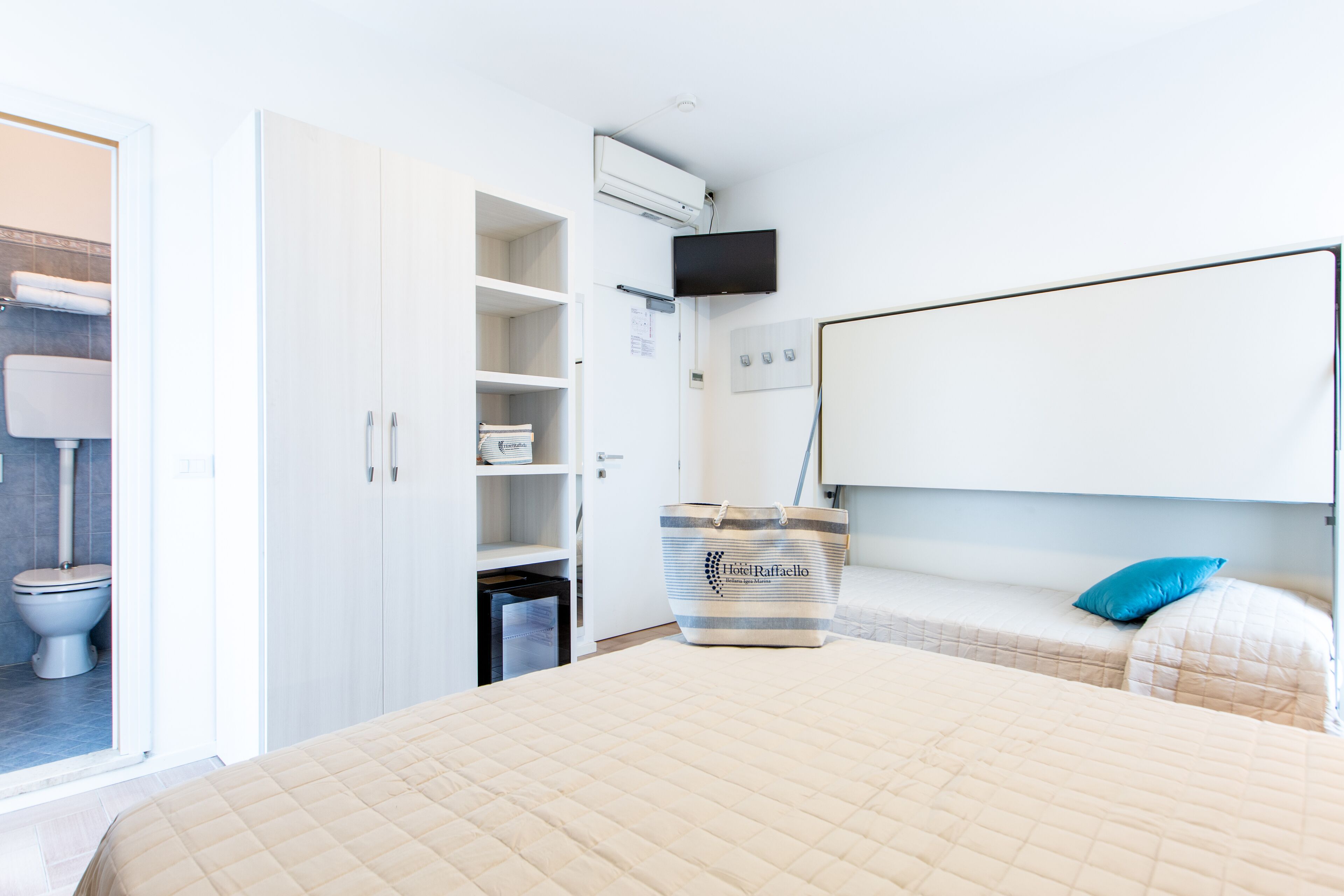 A hotel room with a bed, a wardrobe, a TV, and a bathroom.