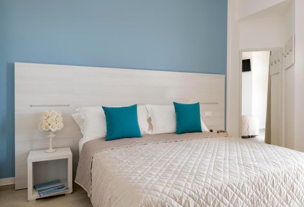 Ein Schlafzimmer mit einem großen Bett, einem Nachttisch mit Blumen und einem weißen Kopfteil.