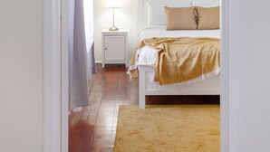 A bedroom with a bed, bedside table, lamp, and a mirror on the wall.