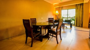 Un coin repas avec une table ronde et des chaises, un ventilateur de plafond et une vue sur la verdure environnante.