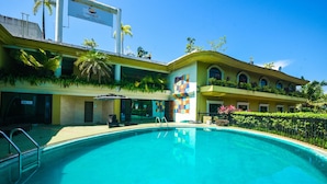 Un hôtel doté d’une piscine, d’une fresque murale aux couleurs vives et d’une enseigne indiquant « Nimbus Neefam The Glitz ».