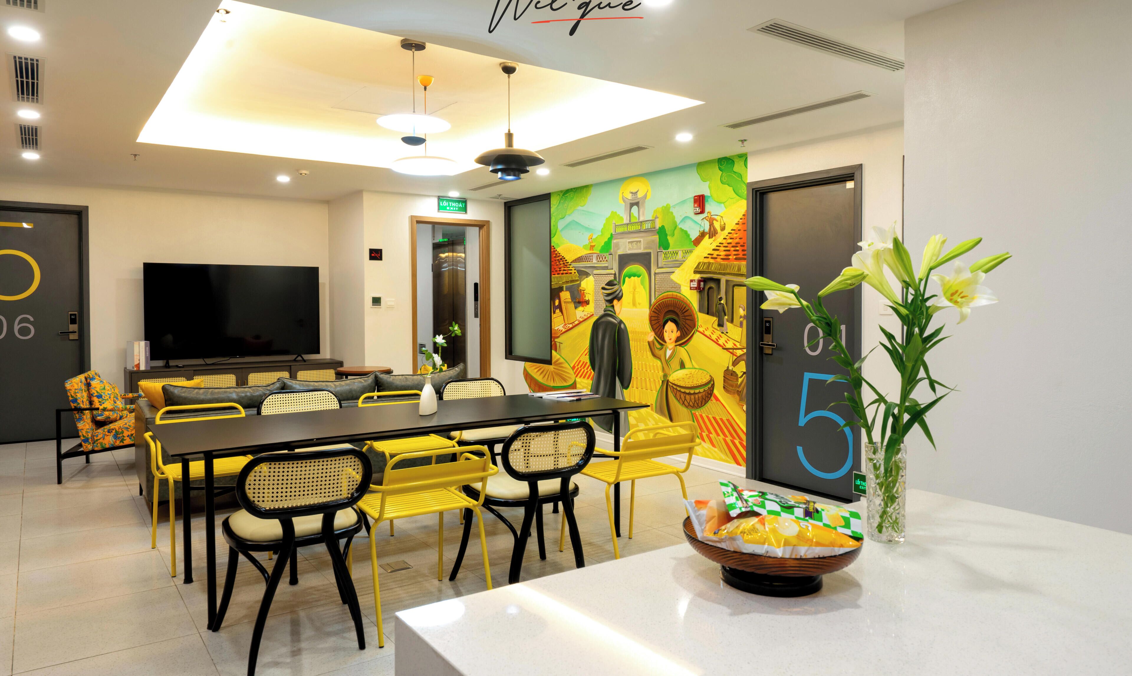 A conference room with a large table, chairs, a television, and a mural on the wall.