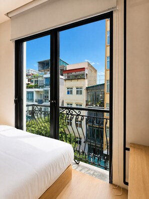 A bedroom with a large window, a bed, and a view of a cityscape. - Wilque Hotel Hanoi (Hanoi)
