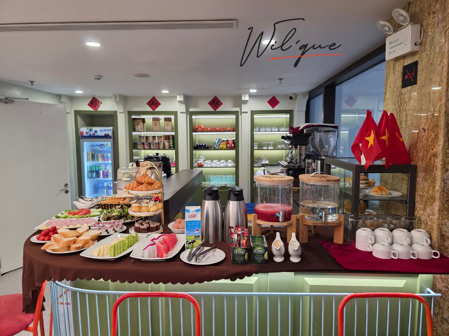 Un área de comida con diversos platos, una estación de café y un letrero que dice 'Welcome'.