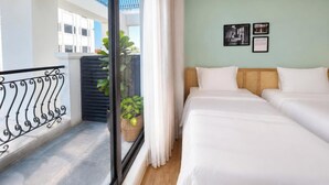 A hotel room with two beds, a balcony with a wrought iron railing, and a view of a building outside. - Wilque Hotel Hanoi (Hanoi)