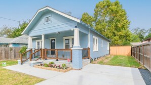 A single-story house with a front porch, a wooden fence, and a well-maintained lawn. - Charming private house sleeps 4 with a large fenced yard, fast WiFi, smart TVs, and ample parking—near the Heights & Downtown. Features a primary king bed for a comfortable stay. (Houston)