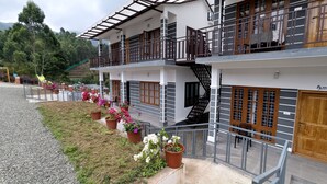 A two-story building with balconies, a staircase, and potted plants. - Moon Wings Mountain Resort (Devikolam)